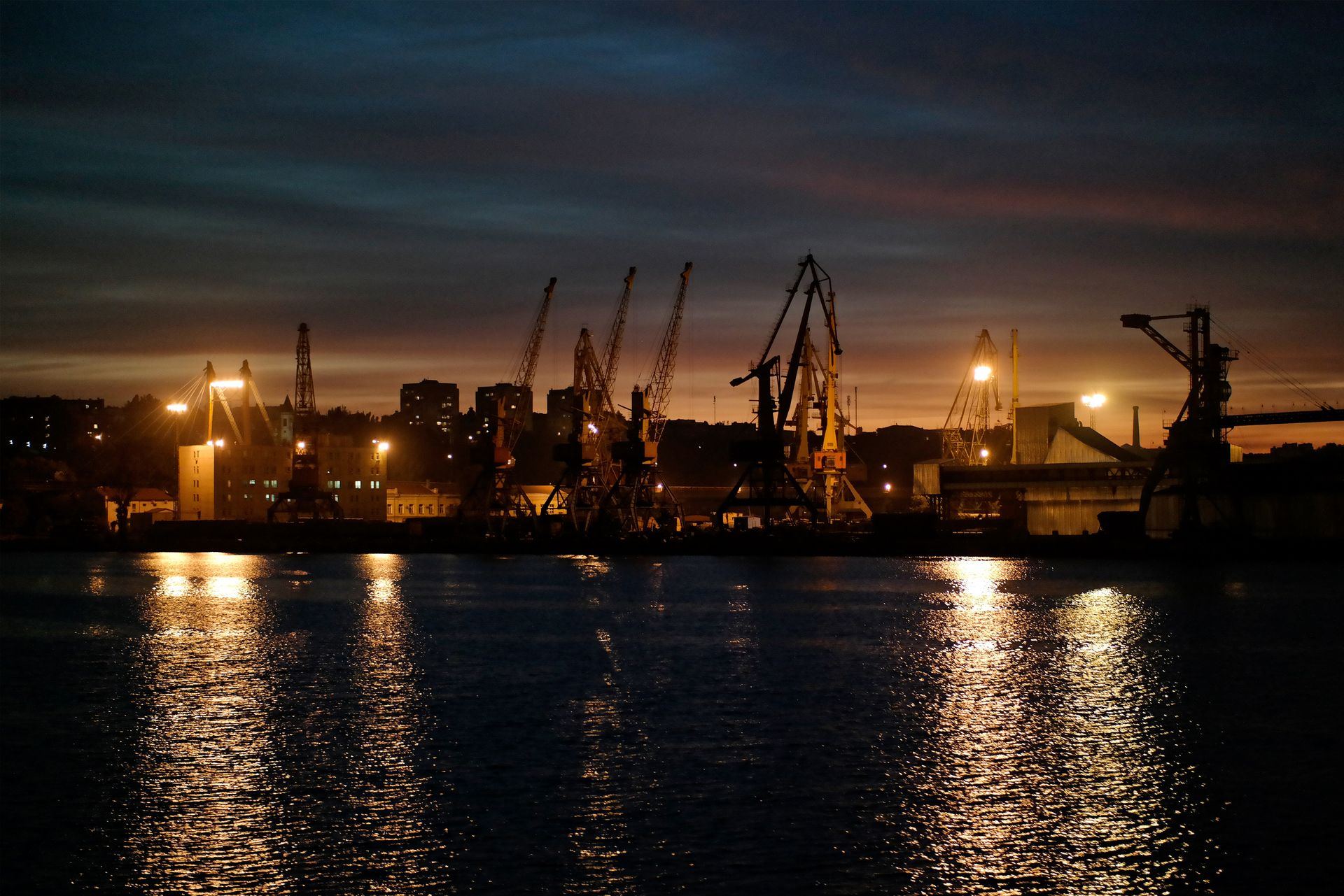 Port cranes silhouetted against the harbor at dusk
